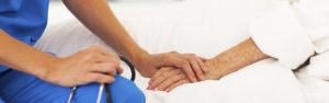 medical doctor holding senior patient's hands and comforting her